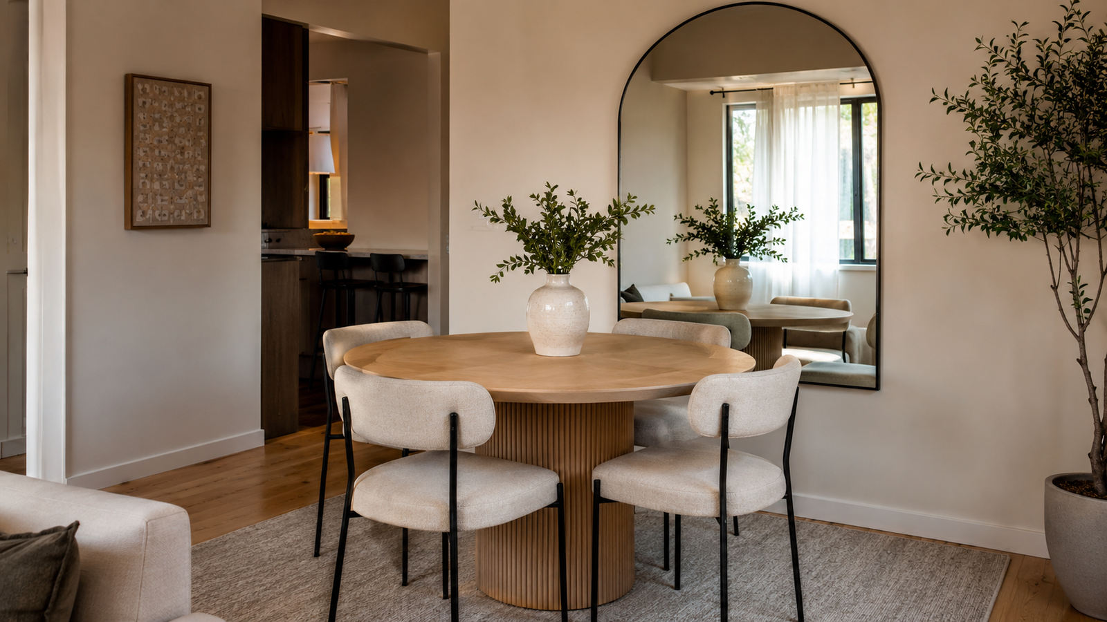 Small dining room with a round pedestal table, slim chairs and a large wall mirror