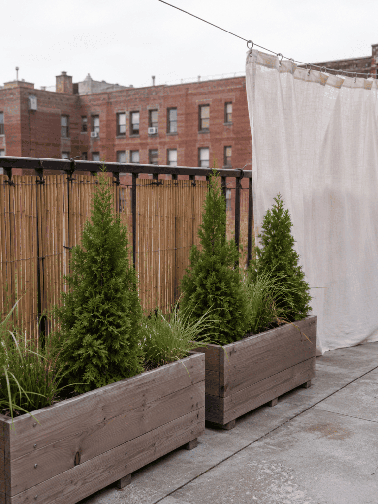 Bamboo reed fencing, cedar planters, and a tension wire curtain creating rooftop privacy