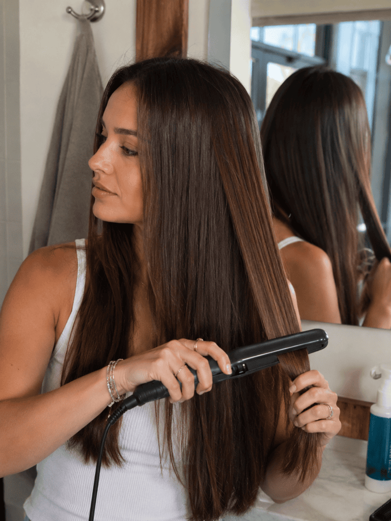 Sleek pin straight long hair being finished with a flat iron