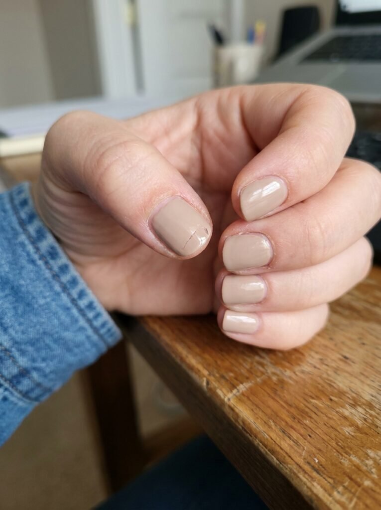 Close up of a slightly chipped neutral manicure showing a common nail mistake