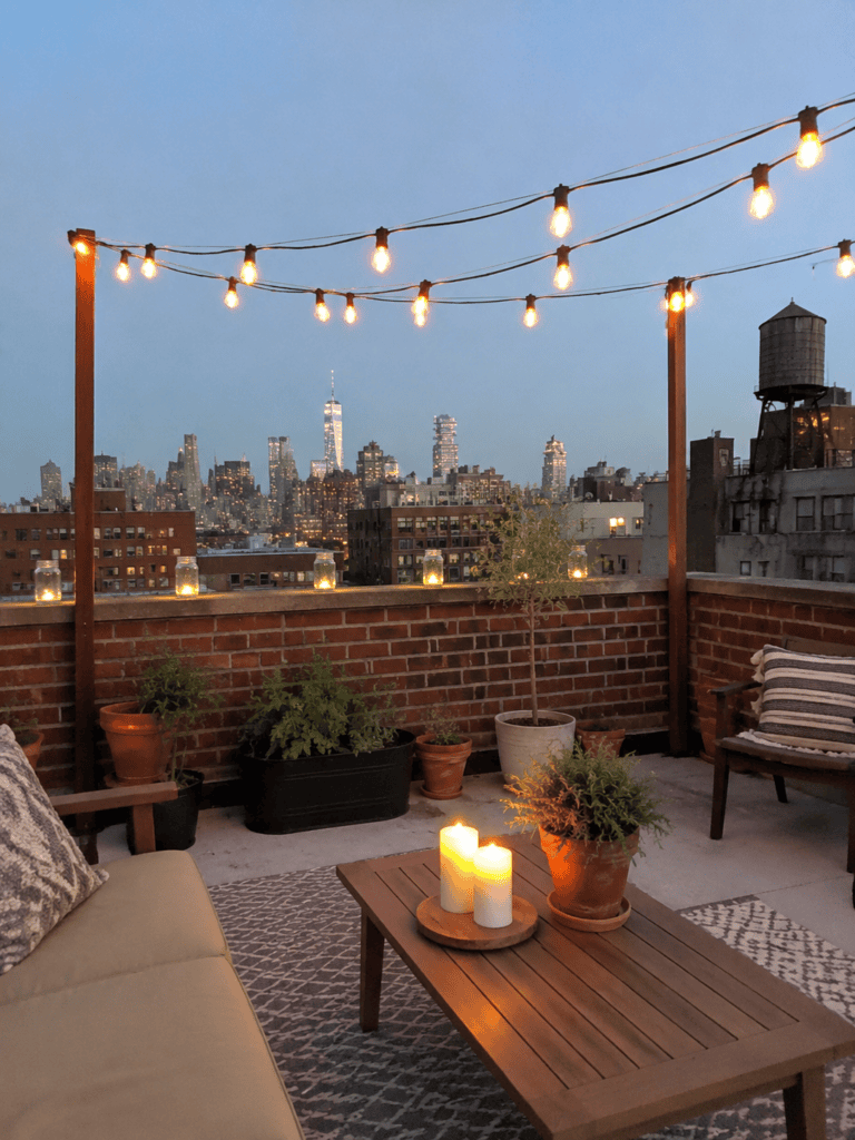 American rooftop at night lit by Edison bulb string lights, mason jar lanterns, and candles