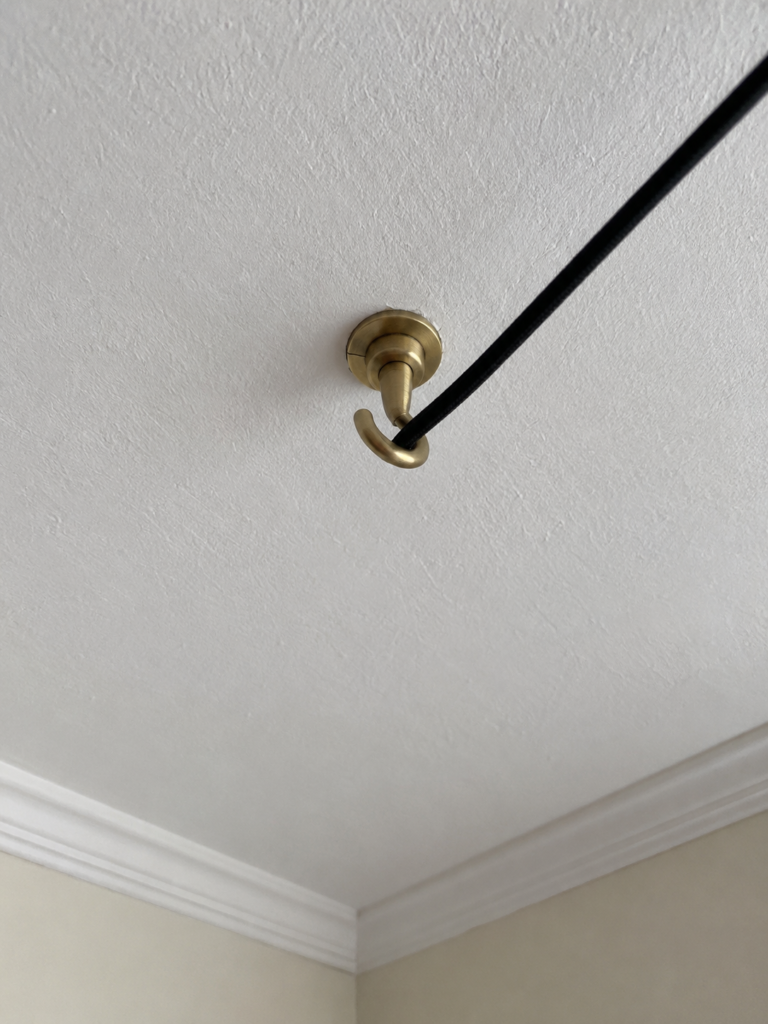 Close view of a ceiling hook fitted with a toggle anchor, with a pendant cord looped through it