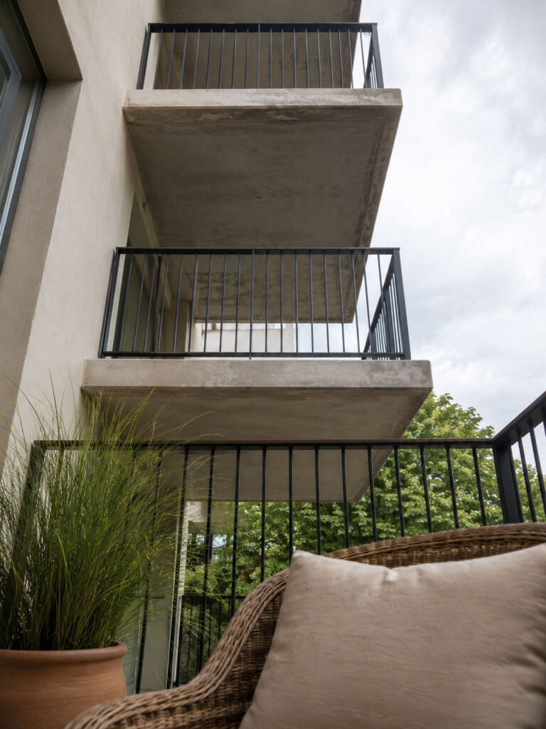 View looking upward from a seated position on a balcony, showing the undersides and railings of two balconies on the floors above