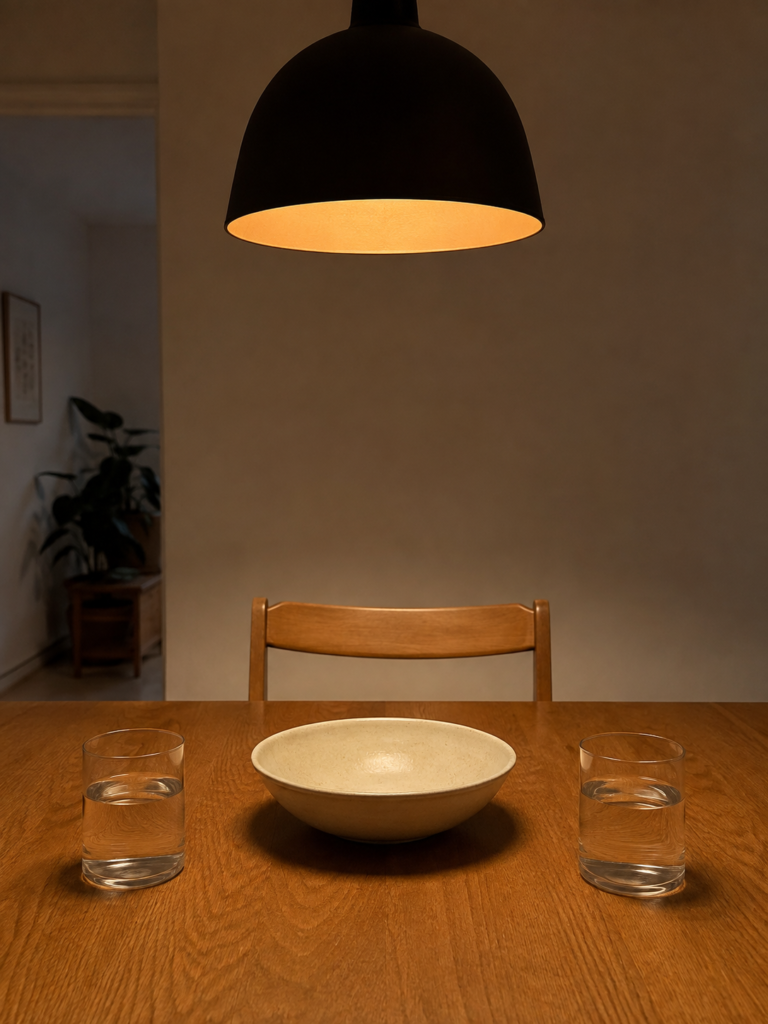 View from a seated position across a dining table, showing a clear line of sight beneath a warm pendant light