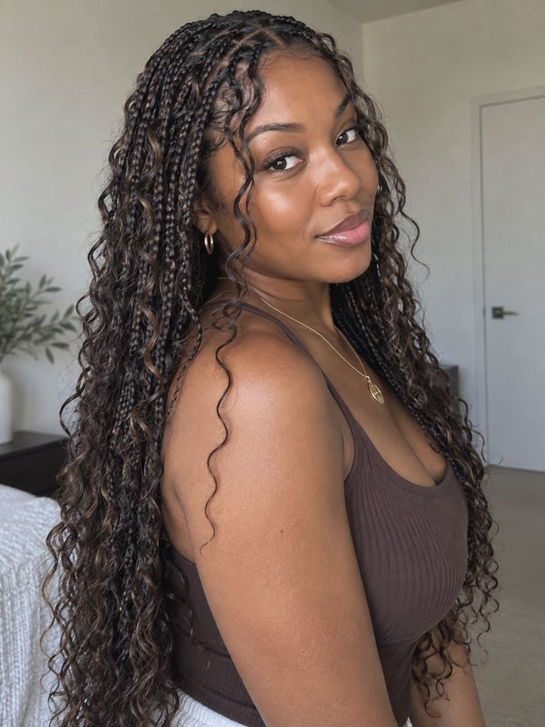Black woman wearing long boho braids with soft curls woven through the braided lengths