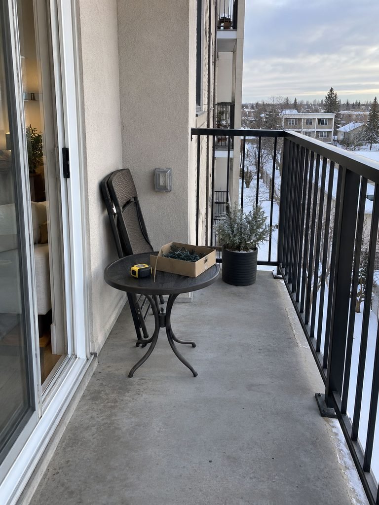Undecorated apartment balcony with railing, outlet, sliding door, and open floor space ready for Christmas planning
